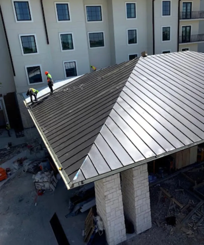 Crew installing standing seam metal roof panels on a commercial project in New Holland